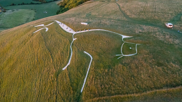 An aerial view above White Horse Hill, with a group of volunteers visible, re-chalking the bronze-age white horse on top of the hill.